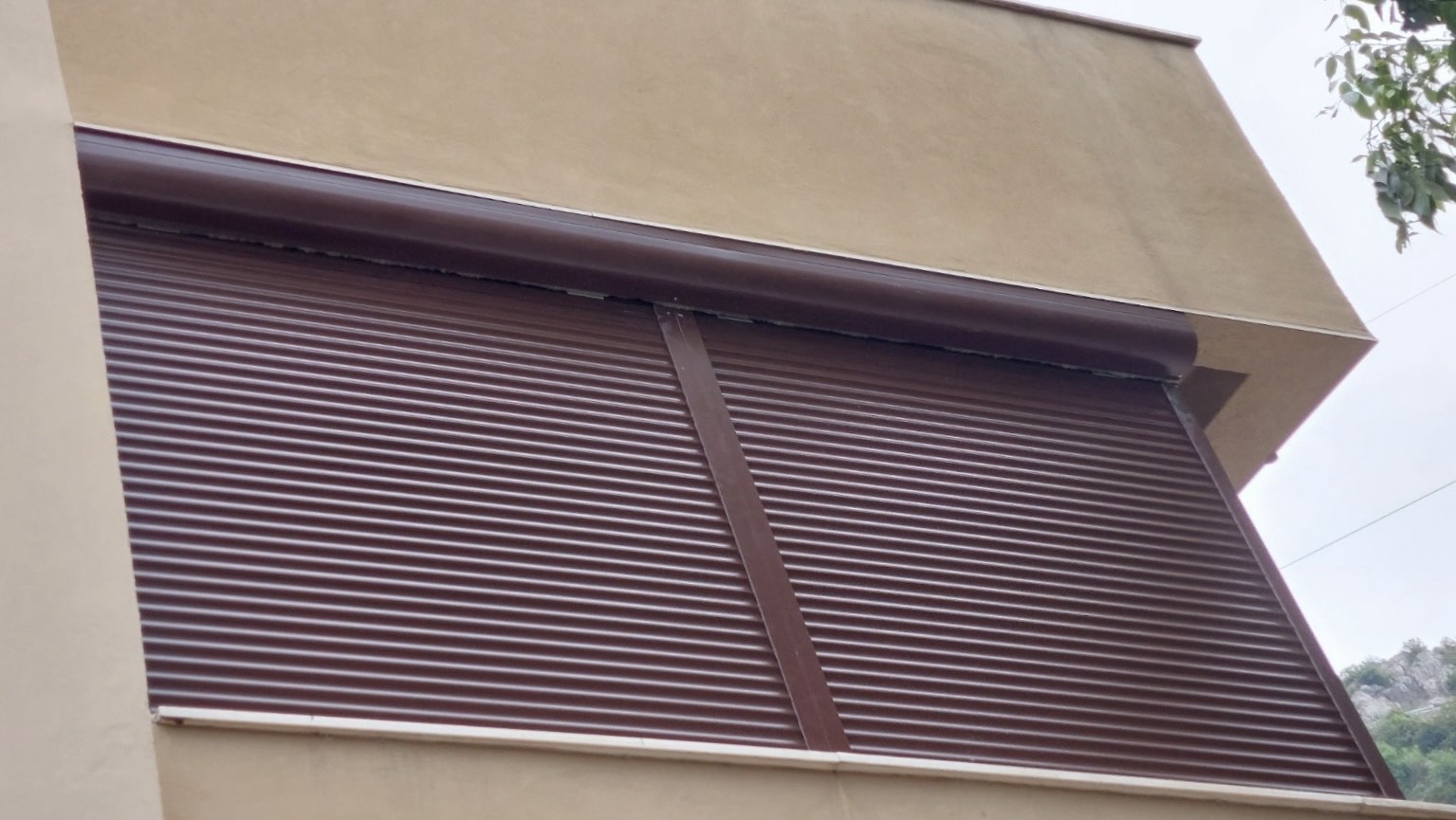 Aluminijumske roletne smeđe boje na prozoru stambene zgrade