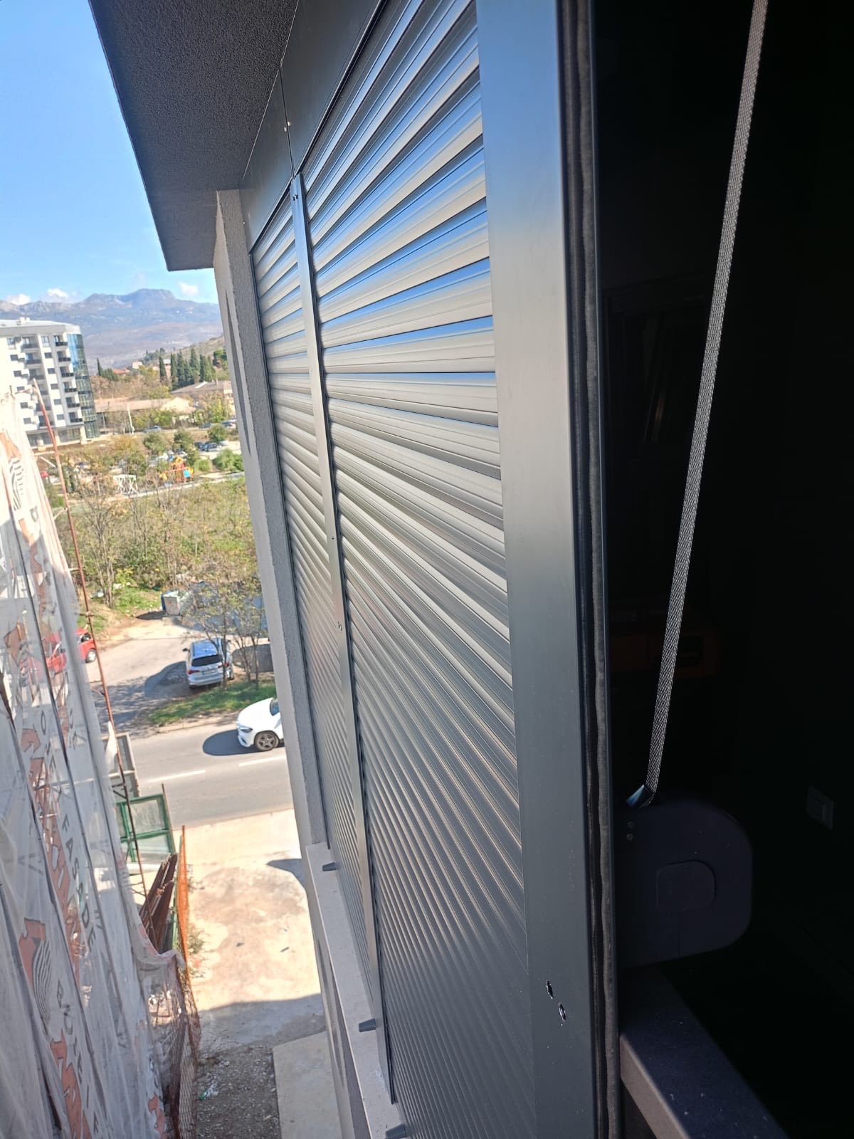 Aluminijumske roletne na balkonskom prozoru stambene zgrade s pogledom na grad